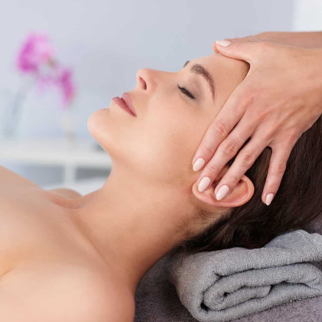 Fizjoestetyka - fizjoterapeutka masuje twarz pacjentki