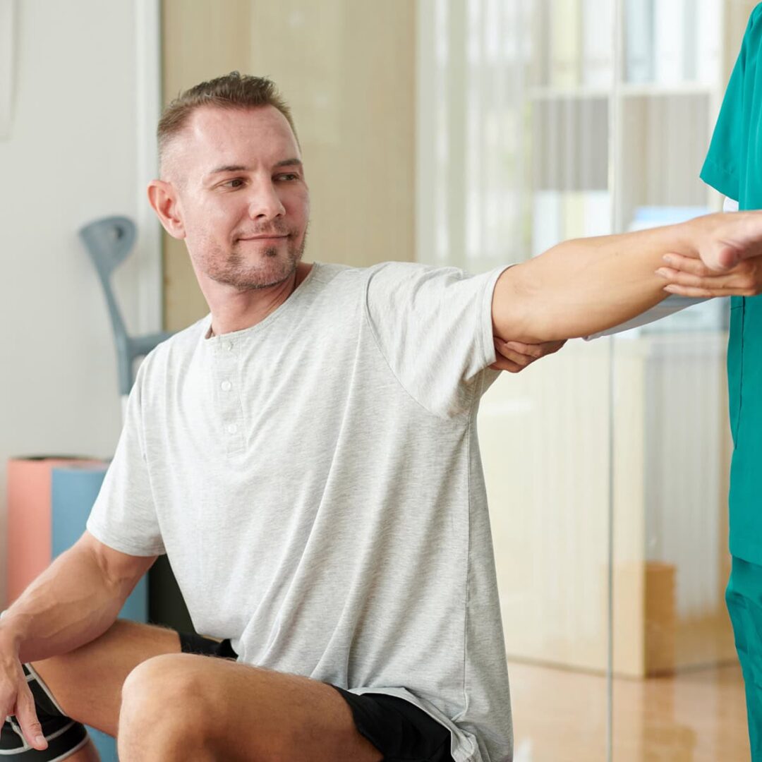 fizjoPS Uwolnij się od bólu - fizjoterapeuta wyprostowuję rękę pacjenta